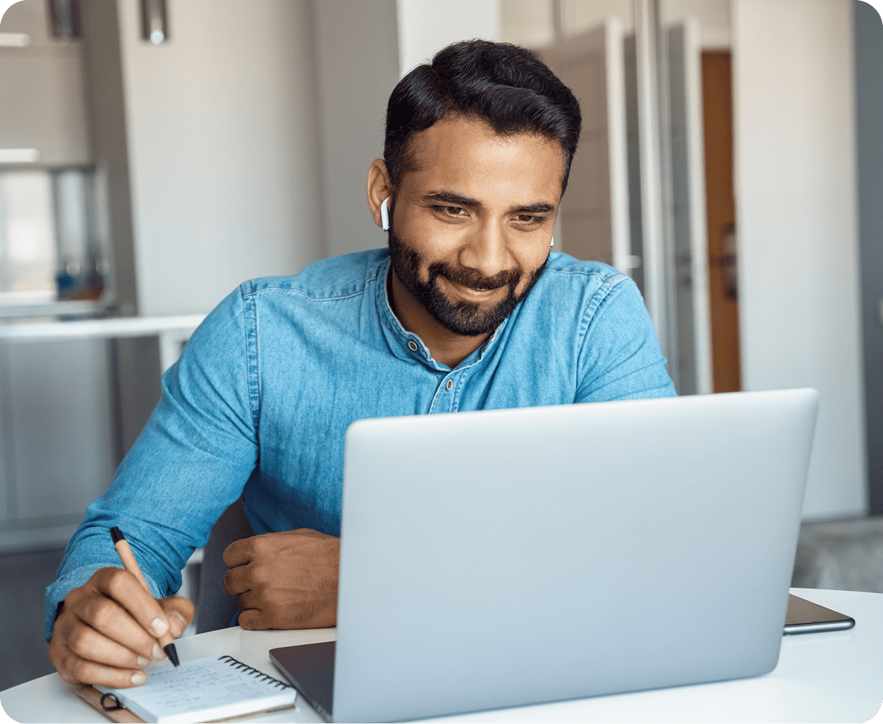 Man working on laptop with notepad